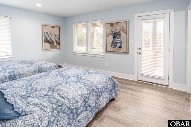 bedroom featuring light wood finished floors, multiple windows, and baseboards