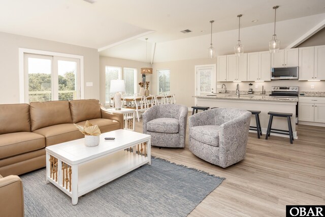 living area with lofted ceiling, visible vents, and light wood-style flooring