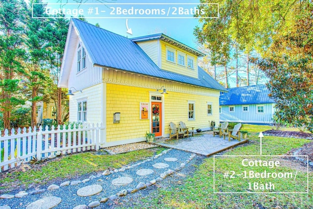 view of front of property featuring a front yard, fence, metal roof, and a patio