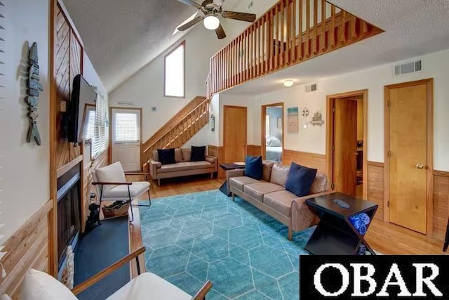 living area with stairway, visible vents, wood finished floors, and wainscoting