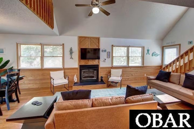 living area with a wainscoted wall, wood walls, a textured ceiling, and light wood-style floors