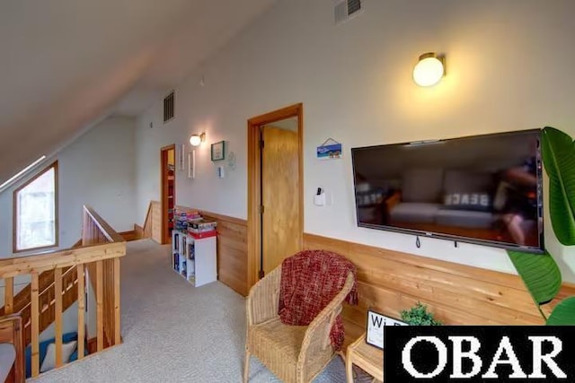 interior space featuring lofted ceiling, a wainscoted wall, carpet, and visible vents