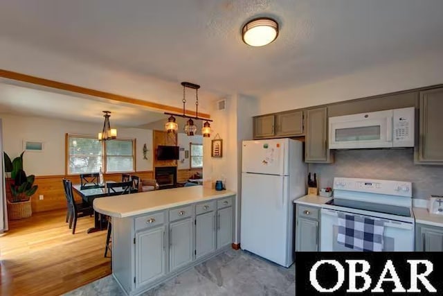 kitchen featuring pendant lighting, visible vents, light countertops, white appliances, and a peninsula