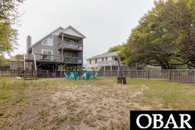 rear view of property with a balcony, fence, stairs, a lawn, and a chimney