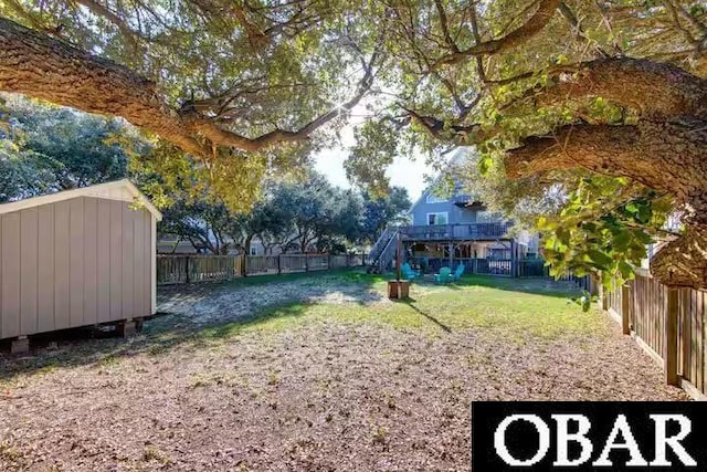 view of yard with an outbuilding, a fenced backyard, stairs, a wooden deck, and a shed