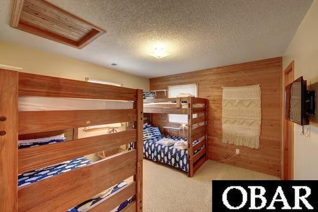 carpeted bedroom featuring wooden walls and a textured ceiling