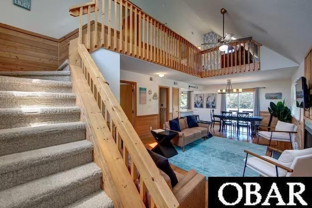 living room featuring ceiling fan, wood walls, wood finished floors, stairway, and wainscoting