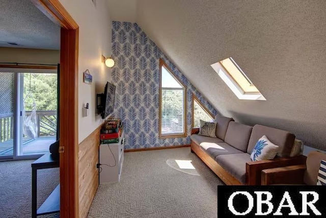 interior space with light colored carpet, lofted ceiling with skylight, a textured ceiling, baseboards, and wallpapered walls