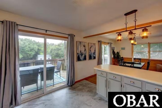 kitchen featuring a wealth of natural light, pendant lighting, light countertops, and white cabinets