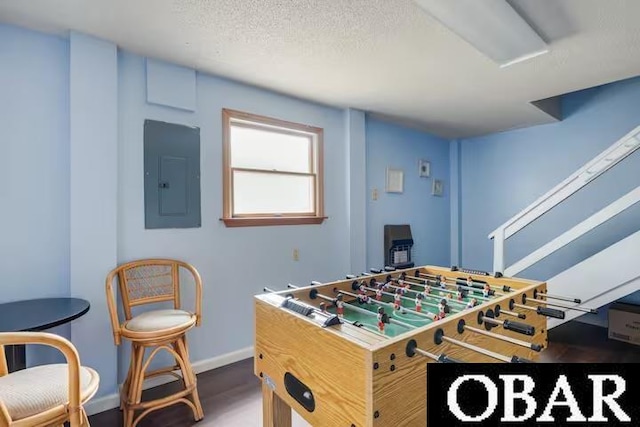 game room featuring a textured ceiling, wood finished floors, electric panel, and baseboards