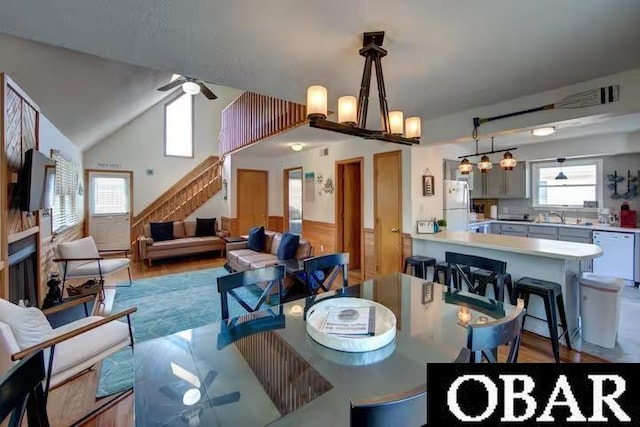 dining area featuring light wood-style flooring, lofted ceiling, ceiling fan, and stairway