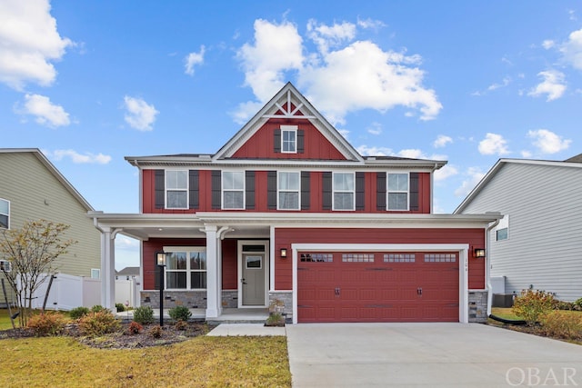 craftsman-style home with a garage, stone siding, covered porch, and concrete driveway