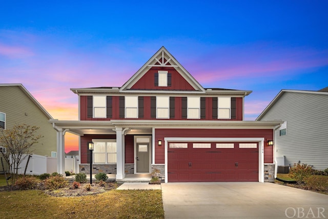 view of front facade featuring board and batten siding, stone siding, driveway, and an attached garage