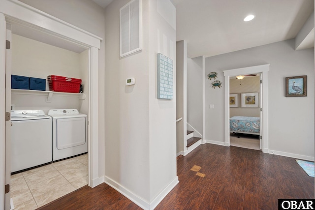 laundry room with visible vents, washing machine and dryer, wood finished floors, laundry area, and baseboards