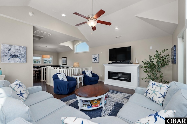 living room featuring lofted ceiling, a glass covered fireplace, dark wood-style floors, and visible vents