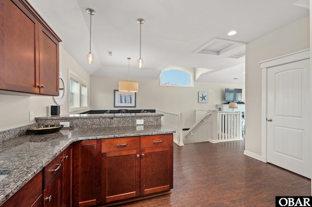 kitchen with lofted ceiling, open floor plan, dark stone counters, dark wood finished floors, and pendant lighting