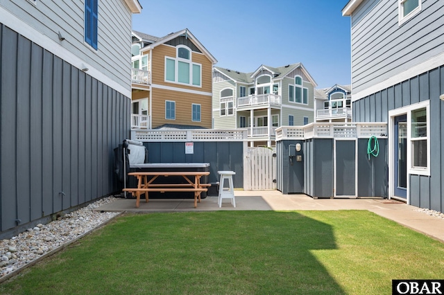 rear view of property featuring board and batten siding, a residential view, and a yard