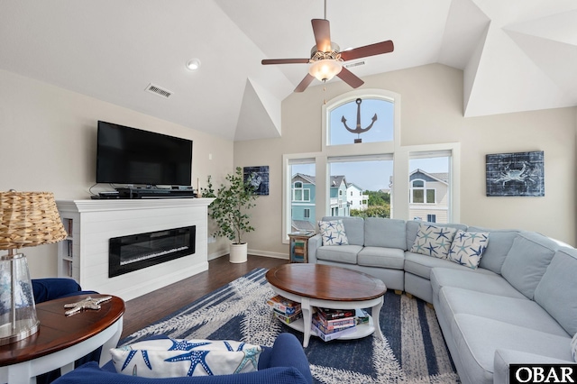 living room featuring baseboards, visible vents, a glass covered fireplace, ceiling fan, and dark wood-type flooring