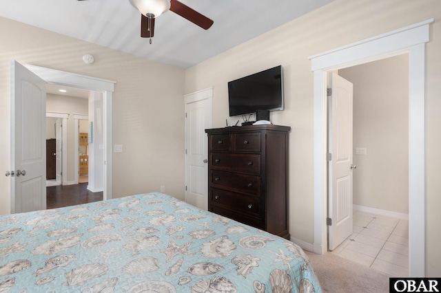 bedroom featuring light carpet, light tile patterned floors, a ceiling fan, and baseboards