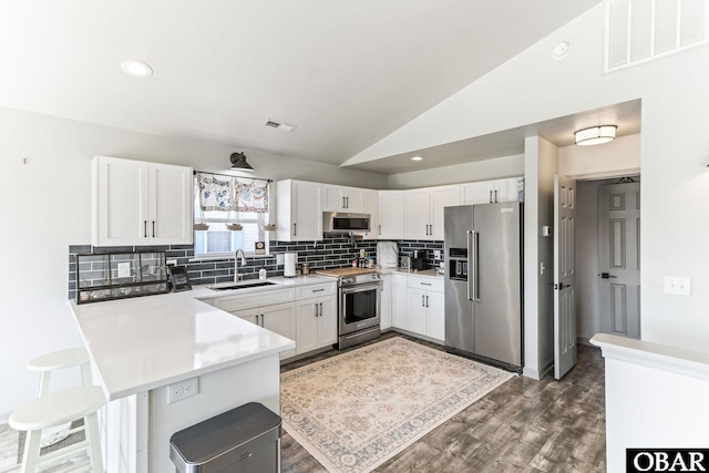 kitchen featuring stainless steel appliances, a sink, a peninsula, decorative backsplash, and light countertops