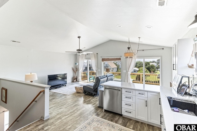 kitchen featuring lofted ceiling, a peninsula, a sink, wood finished floors, and dishwasher