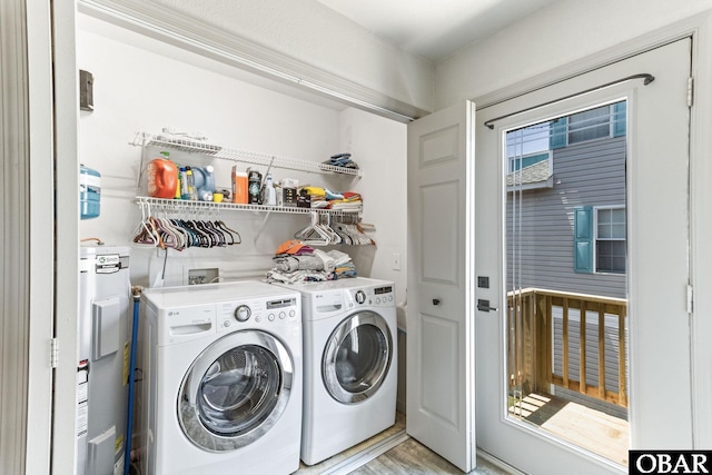 laundry room featuring water heater, washing machine and clothes dryer, and light wood-type flooring