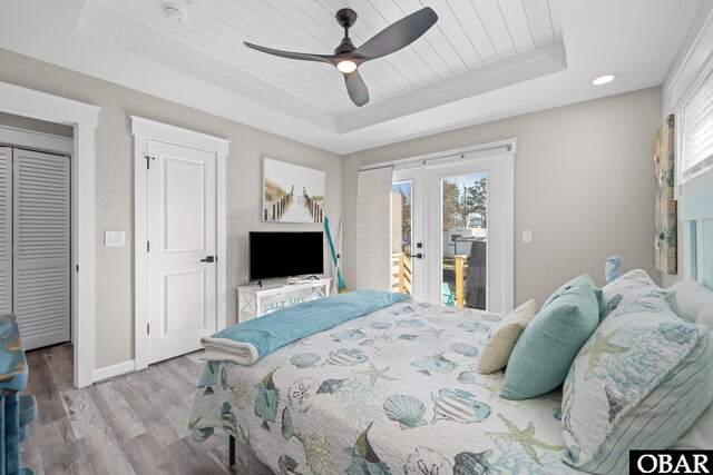 bedroom with access to exterior, a raised ceiling, wooden ceiling, and light wood finished floors