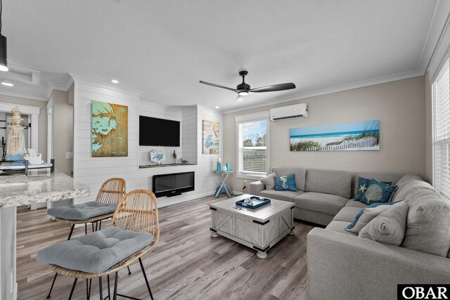 living room with a large fireplace, ornamental molding, wood finished floors, and a wall mounted air conditioner