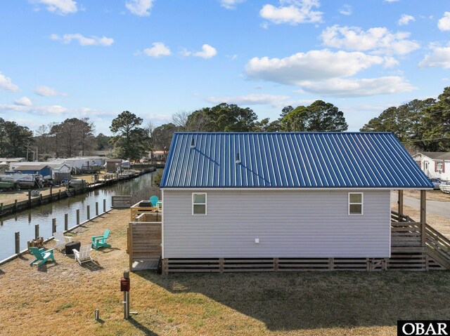 view of side of home featuring metal roof and a water view