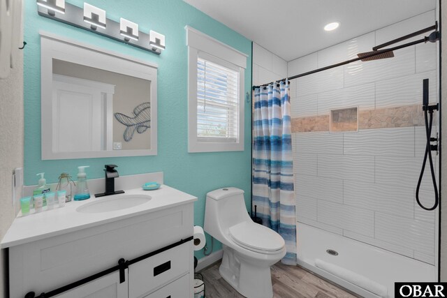 bathroom featuring toilet, a stall shower, wood finished floors, and vanity