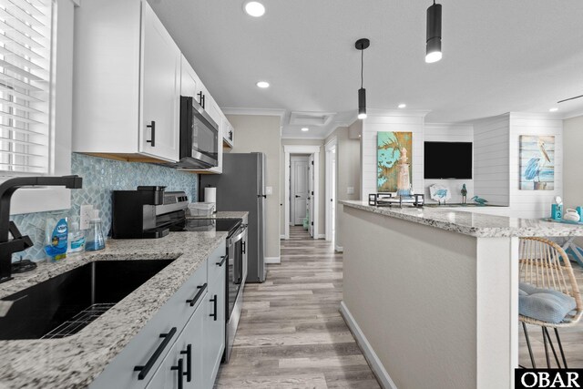 kitchen featuring a kitchen bar, appliances with stainless steel finishes, white cabinetry, and a sink