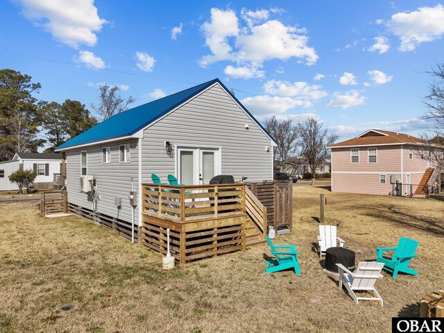 rear view of house with a deck, a lawn, and french doors