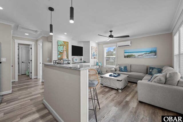 living area featuring recessed lighting, ornamental molding, an AC wall unit, light wood-type flooring, and baseboards