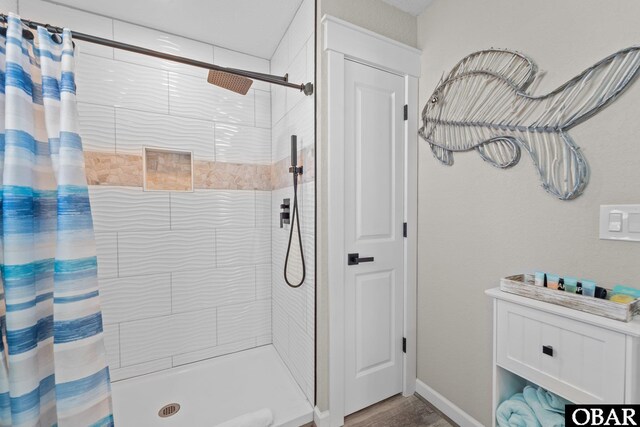 full bath with a stall shower, baseboards, and wood finished floors