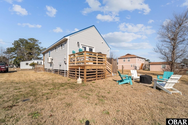 rear view of house with a fire pit, a yard, and a deck