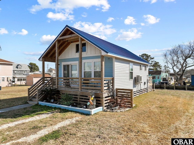 view of front facade featuring board and batten siding, a front yard, and metal roof