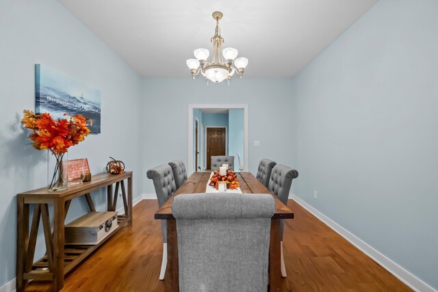 dining room featuring baseboards, an inviting chandelier, and wood finished floors