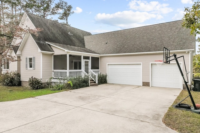 view of front of home with roof with shingles, covered porch, a garage, a sunroom, and driveway