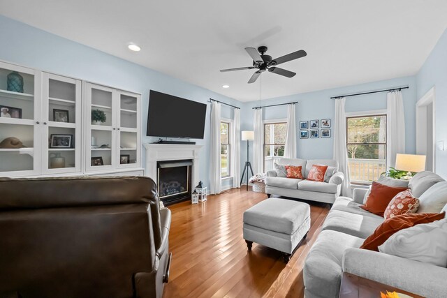 living area featuring a fireplace, recessed lighting, wood finished floors, and ceiling fan