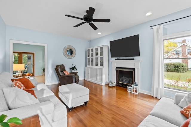 living area featuring a ceiling fan, wood finished floors, recessed lighting, a fireplace, and baseboards