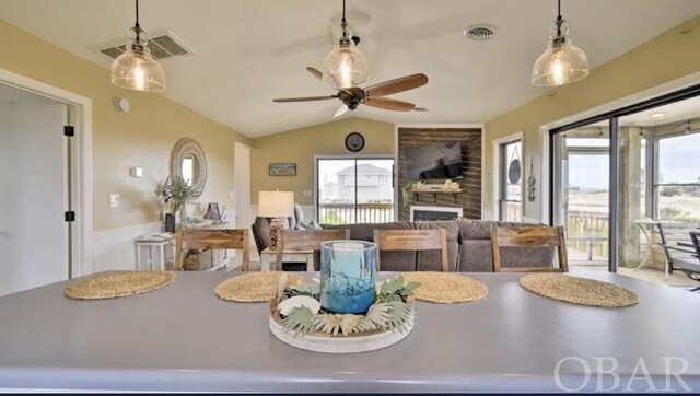 dining space featuring vaulted ceiling, a fireplace, visible vents, and a healthy amount of sunlight