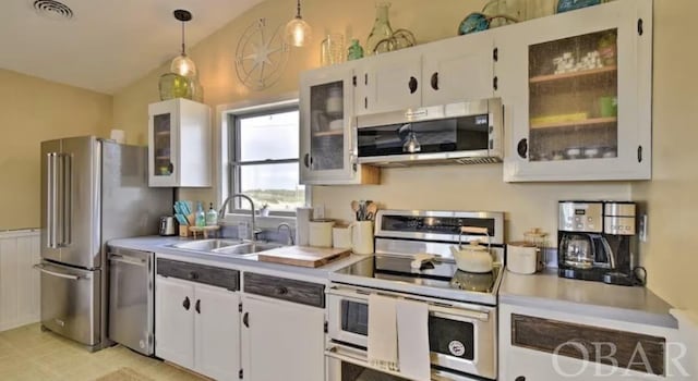 kitchen featuring pendant lighting, light countertops, appliances with stainless steel finishes, glass insert cabinets, and white cabinetry