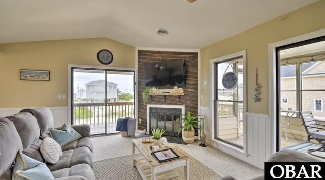 carpeted living area featuring wainscoting, a fireplace, and a wealth of natural light