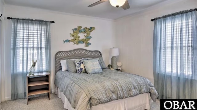 carpeted bedroom with ornamental molding and ceiling fan