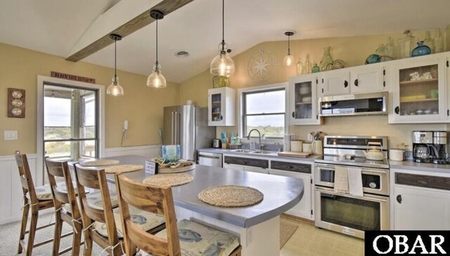 kitchen featuring a sink, white cabinets, appliances with stainless steel finishes, range hood, and decorative light fixtures