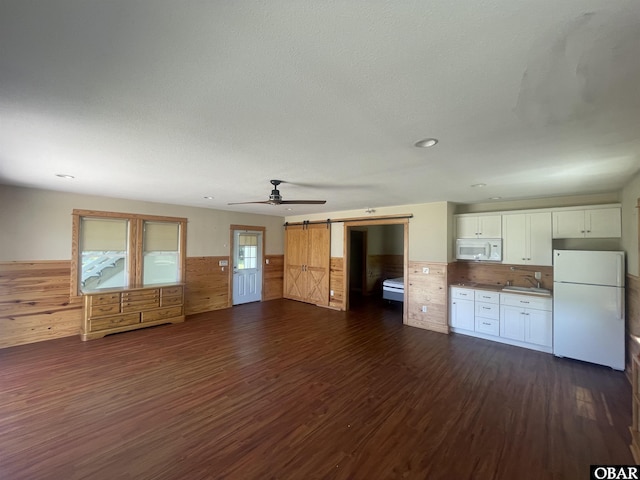 102 Daybreak Ct Lot # 53, Grandy, NC 27939 - unfurnished living room featuring a wainscoted wall, a barn door, dark wood finished floors, ceiling fan, and wood walls
