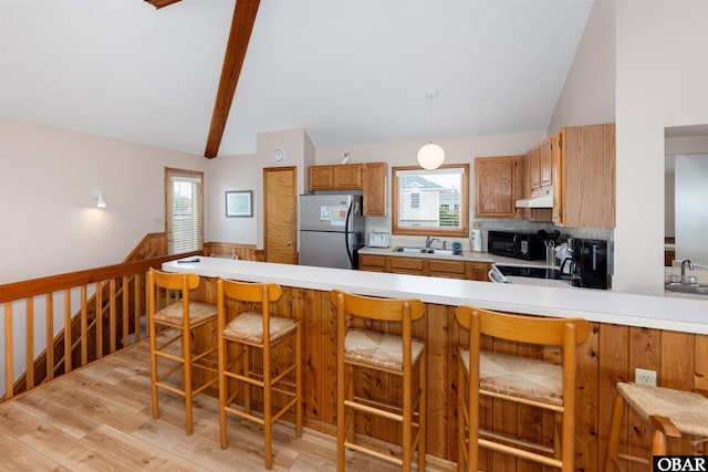 629 Sanderling Trl Lot 51, Corolla, NC 27927 - kitchen with freestanding refrigerator, under cabinet range hood, light wood-type flooring, black microwave, and light countertops