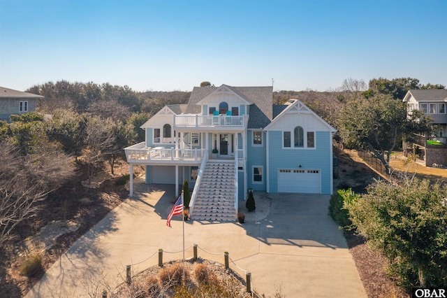 view of front of house with covered porch, concrete driveway, stairway, a balcony, and a garage