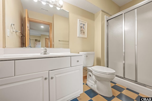 full bath featuring toilet, vanity, visible vents, a shower stall, and tile patterned floors