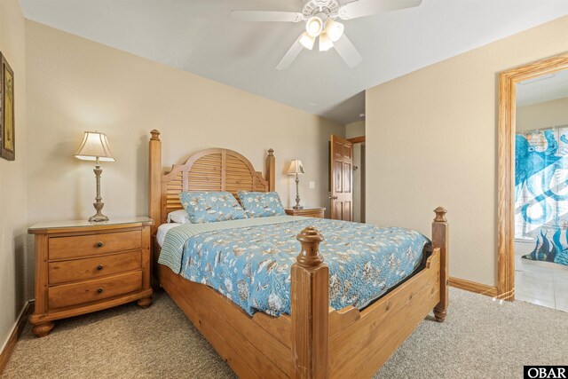 bedroom featuring light carpet, ensuite bath, a ceiling fan, and baseboards